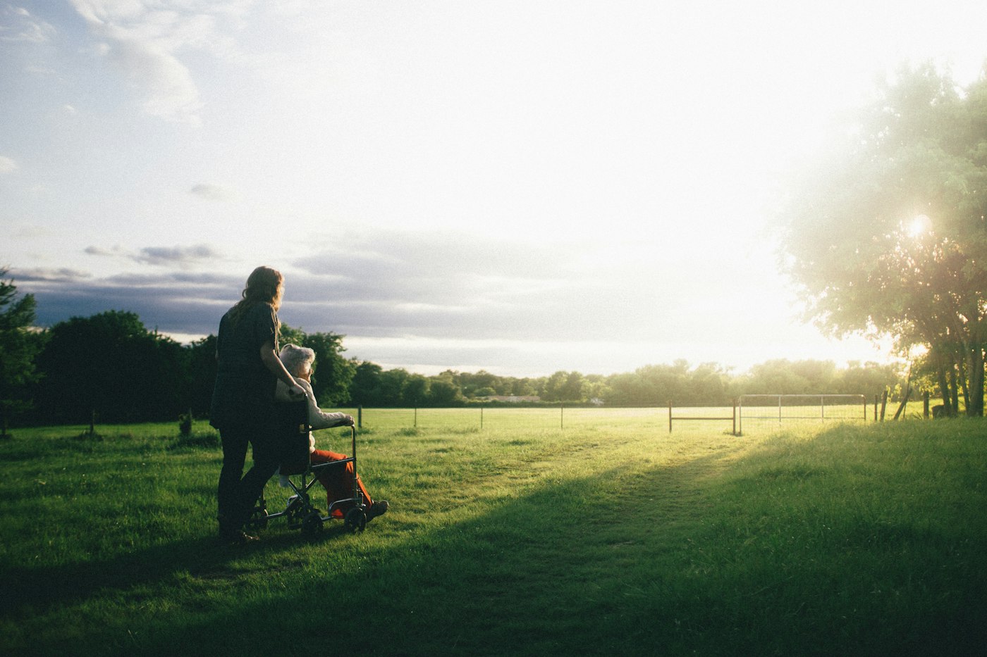 A companion walking beside an older adult in a wheelchair